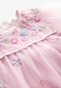 Rosa Tüllkleid mit floraler Bestickung in Pink, Blau und Grün. Mit einer Spitzenborte an der Taille und einem runden Ausschnitt.