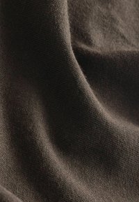 Material maro închis cu o textură moale, fin tricotată și pliuri ușoare care creează umbre și lumini subtile.