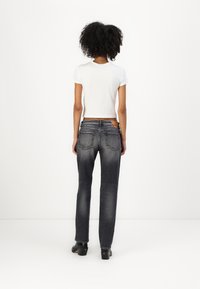 Gray denim jeans with a straight-leg cut, back pockets, and subtle fading; worn with a white fitted t-shirt and black heeled shoes.