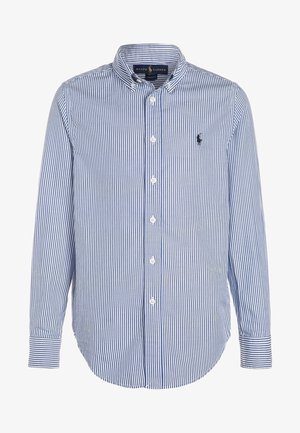 Koszula w paski w kolorze niebieskim i białym, z długim rękawem, kołnierzykiem na guziki, logo na piersi oraz zaokrąglonym dołem; wykonana z lekkiej bawełnianej tkaniny.
