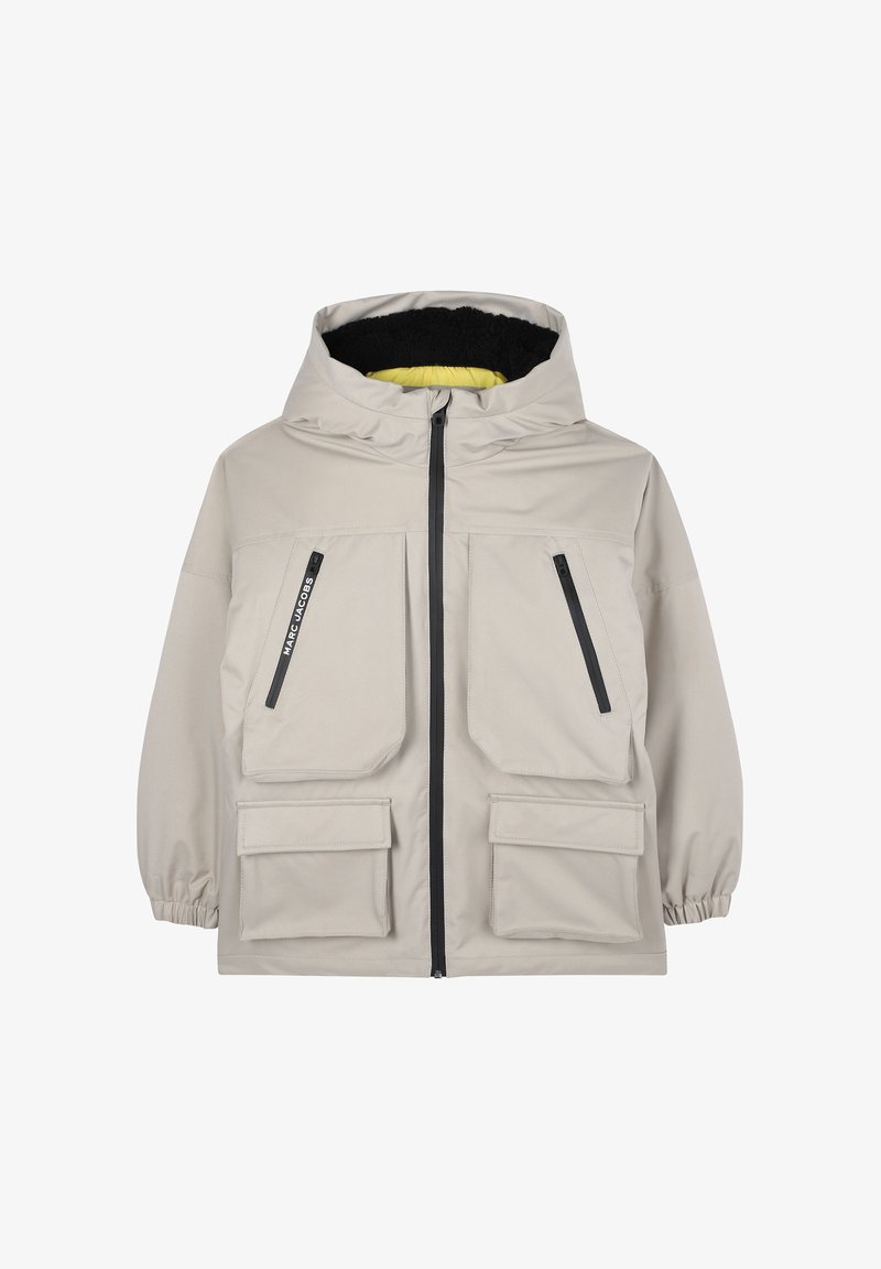 Beige waterproof jacket with a hood, featuring two large front pockets, two side zip pockets, and contrast black and yellow lining.