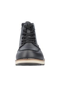 Chaussure en cuir noir à lacets avec surface texturée, bout rond et semelle en caoutchouc blanche. Dispose d'une fermeture éclair sur le côté pour un enfilage facile.