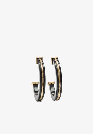 Czarne kolczyki koła z centralnym złotym łańcuszkiem i złotymi kwadratowymi zakończeniami, prezentowane na białym tle.