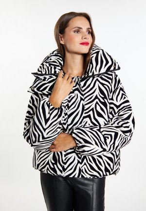 Giacca a vento imbottita a motivo zebra in bianco e nero, con colletto alto, zip frontale e polsini elasticizzati. Il tessuto appare lucido e testurizzato.