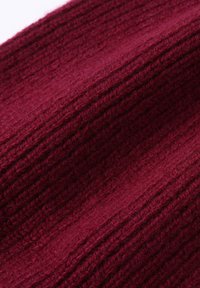 Burgundy knit fabric with a ribbed texture and slight sheen. Material appears soft, with visible fibers and subtle depth in color.