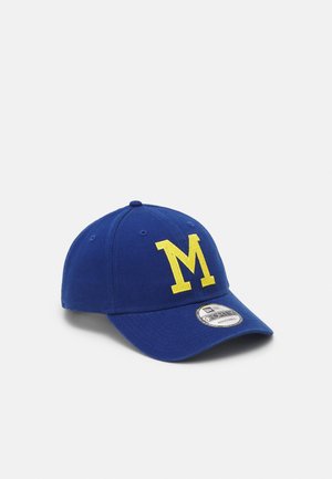 Blaue Baseballkappe mit großem gelbem "M" auf der Vorderseite und verstellbarem Riemen unter dem gebogenen Schirm.