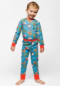 Children's pajamas made of soft fabric, featuring a bright blue pattern with gingerbread men, candy canes, and ornaments. Red accents at cuffs.