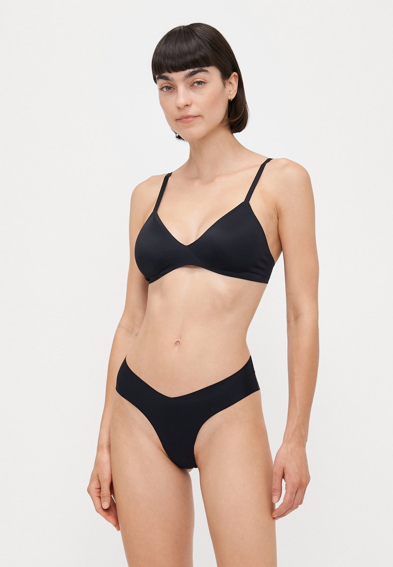 Set di bikini nero composto da un reggiseno triangolare con spalline sottili e slip a vita bassa. Tessuto liscio e elastico con un design minimalista.