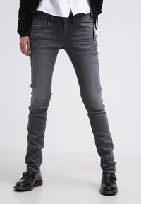 Grå slim-fit jeans i denim, med fem fickor, subtila slitningar och en mjuk textur. Kombineras med svarta skor.