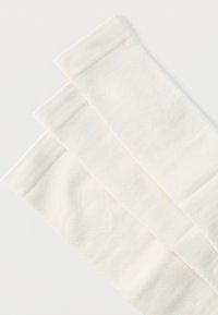 Τρία διπλωμένα λευκά υφασμάτινα πετσέτα με διακριτό υφασμάτινο μοτίβο, τοποθετημένα διαγώνια σε λευκό φόντο.