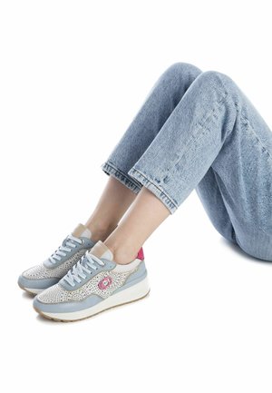Zapatillas de deporte azul claro con paneles perforados blancos, detalles rosas en el talón y suela blanca; combinadas con jeans de mezclilla claros y recortados.