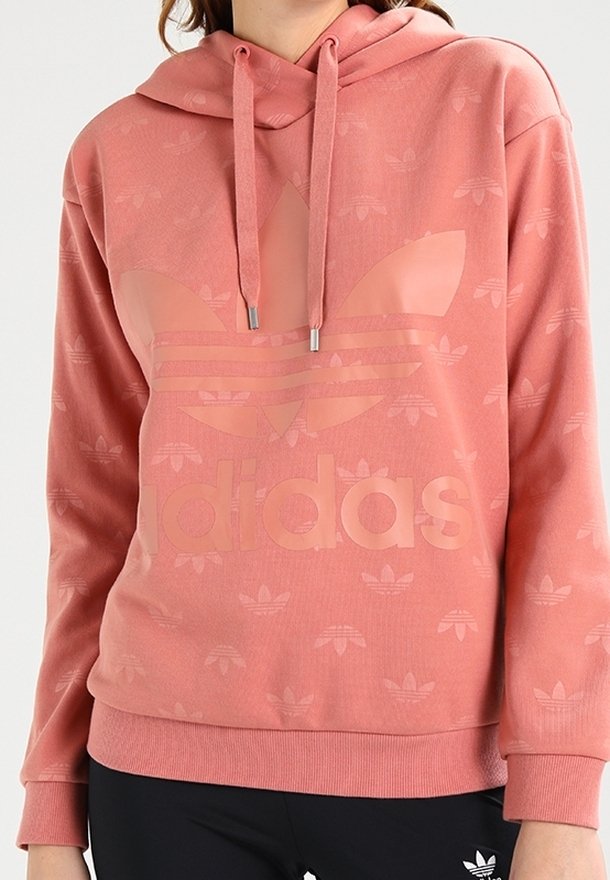 Rosa hoodie med en stor Adidas-logotyp, tillverkad av mjukt tyg med ett subtilt mönster av små logotyper i hela plagget. Justerbar dragsko i huvan.