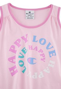 Canotta senza maniche di un rosa chiaro con un motivo circolare delle parole "HAPPY" e "LOVE" in vari colori. Presenta il logo Champion. Tessuto in cotone morbido.