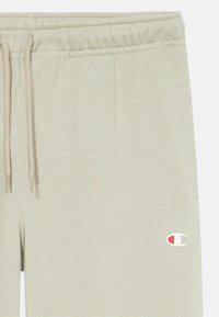 Hellgraue Jogginghosen aus weichem Material, mit einem elastischen Bund und Kordelzug sowie einem kleinen gestickten Logo an der Seite.