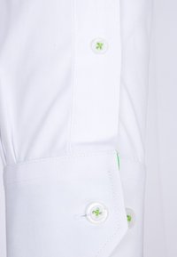 Bílý rukáv košile s knoflíkovým zapínáním, s kontrastním zeleným knoflíkem a vyšívaným detailem, hladká textura, střihaný střih.
