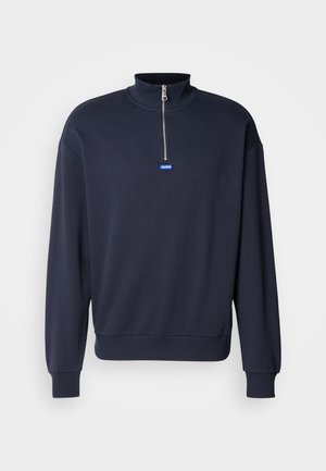 Marinblå sweatshirt med hög krage och halvdragkedja, med ribbade ärmslut och nederkant, samt en liten blå logotyp på framsidan.