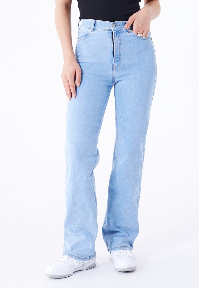 Light blue high-waisted jeans with a straight-leg design, featuring metal button closure, belt loops, and side pockets. Worn with white sneakers.