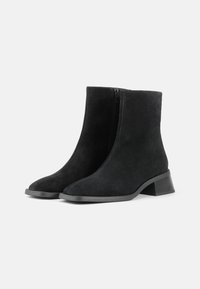 Sorte semskede ankel støvler med blokhæl, lynlås lukning, glat tekstur og spids tådesign. Minimalistisk stil uden mønstre eller accenter.