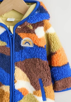 Jachetă din fleece pufoasă, multicoloră, cu accente albastre, dotată cu glugă, închidere cu fermoar și o aplicație rotundă cu un design arc-en-ciel.