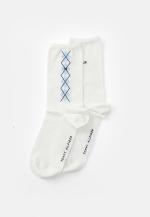 Weiße Baumwollsocken mit einem blauen Argyle-Muster und roten Akzenten. Der Markenname "TOMMY HILFIGER" ist in Marineblau nahe dem Bündchen aufgedruckt.