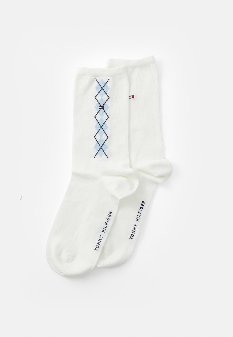Vita bomullssockor med ett blått argyle-mönster och röda accenter. Märkesnamnet "TOMMY HILFIGER" är tryckt i marinblått nära skaftet.