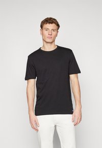 T-shirt nera a maniche corte, con collo a giro, realizzata in tessuto di cotone. Presenta un design semplice senza pattern o loghi visibili.