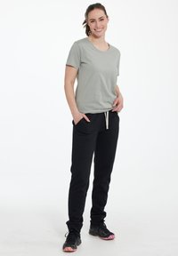 Ljusgrå t-shirt med kort ärm, kombinerad med svarta sweatpants. Sweatpants har dragsko och två sidofickor. Svarta skor med rosa accenter.