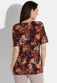 Kurzärmliges Oberteil in Dunkelnavy mit einem mehrfarbigen Blumenmuster in Orange-, Pink- und Brauntönen; weicher, strukturierter Stoff.