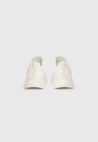 Zapatillas blancas con un upper liso, suela acolchada y una lengüeta en la parte trasera. Diseño minimalista con suaves acentos en tonos pastel en los talones.