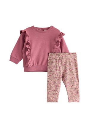 Pinkes Langarmshirt mit Rüschen, kombiniert mit beigen Leggings, die mit einem kleinen pink-braunen Blumenmuster für ein Kleinkind bedeckt sind.
