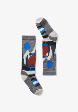 Grå sokker med geometriske mønstre i rød, blå og hvid. Lavet af blødt materiale med kontrasterende stribede og ensfarvede sektioner.