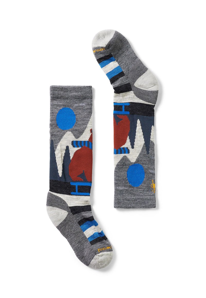 Calcetines grises con patrones geométricos en rojo, azul y blanco. Están hechos de un material suave y presentan secciones a rayas y lisas en contraste.