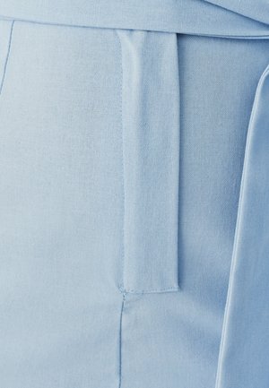 Šviesiai mėlyna medžiaga su lygiu paviršiumi, turinti juosmens raištį ir pritaikytą kirpimą. Detalės apima šoninį kišenę ir siuvinėtus akcentus.