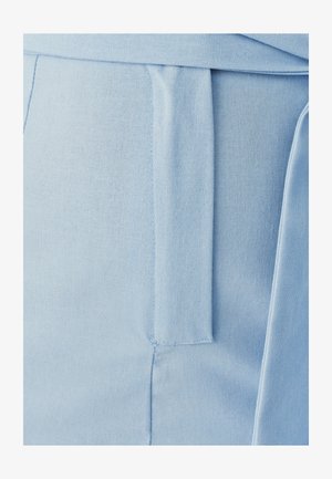 Light blue fabric with a smooth texture, featuring a waist tie and a tailored fit. Details include a side pocket and stitched accents.