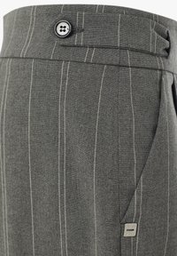 Pantaloni grigi a righe realizzati in un tessuto con una texture liscia. Presentano una chiusura anteriore con bottone e un piccolo etichetta in metallo sul lato.