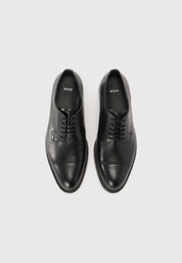 Black leather dress shoes with a smooth texture, rounded toe, and lace-up design; features subtle stitching and embossed logo inside.