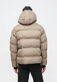 Μπεζ μπουφάν τύπου puffer με αποσπώμ�ενη κουκούλα, καπιτονέ σχέδιο και ελαστικά μανίκια. Διαθέτει ομαλή, ματ υφή και εφαρμοστή σιλουέτα.