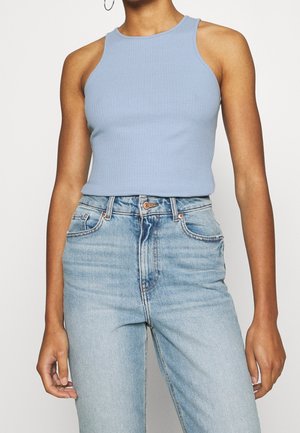 Camiseta de tirantes azul claro con cuello alto y diseño sin mangas, combinada con vaqueros de mezclilla azul desgastados de talle alto.