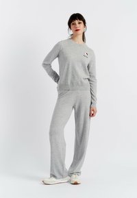 Grijze katoenen sweatshirt met lange mouwen en ronde hals, voorzien van een klein geborduurd logo. Gepaarde met bijpassende grijze wijde broek.