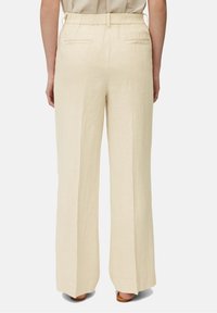 Lichtbeige wijde broek gemaakt van textuurstof. Bevat een elastische tailleband en twee achterzakken.