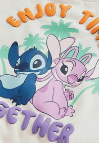 T-shirt con una grafica colorata dei personaggi dei cartoni animati Stitch e Lilo, con lettering testurizzato che legge "GODITI IL TEMPO INSIEME" in arancione e viola.