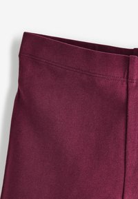 Burgundin väriset leggingsit, joissa on sileä pinta ja joustava kangas. Vyötärönauha on litteä ja saumaton, suunniteltu tarjoamaan mukavuutta ja hyvää istuvuutta.
