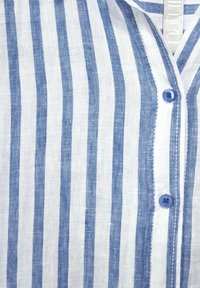 Skjorta med knappar framtill i lätt linne. Har vertikala blåa och vita ränder, blå knappar och en krage. Mjuk textur och avslappnad design.