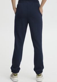 Mörkblå sweatpants i mjukt tyg, med elastisk midja, sidfickor och elastiska muddar vid anklarna.
