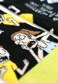 Calze nere con grafiche di cartoni animati che raffigurano personaggi sorpresi, con accenti giallo chiaro e una texture in maglia morbida.