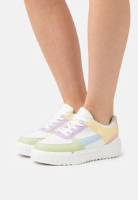 Baskets multicolores avec des panneaux blancs, vert pastel, jaunes et violets ; bout arrondi, design perforé et semelle blanche texturée.
