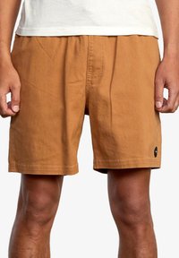 Shorts in cotone marrone con vestibilità rilassata, dotati di una vita elastica e di una piccola etichetta nera sul lato sinistro.