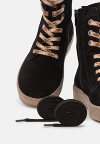 Sneaker alte nere in suede con lacci beige, suola in gomma texturizzata e estremità dei lacci in argento. Include lacci neri aggiuntivi.