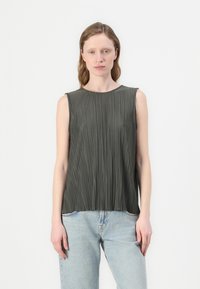 Utenermet mørke oliven grønn topp med vertikale folder, rund utringing og glatt tekstur, parret med lyseblå rette jeans.