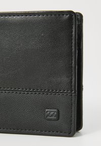 Portafoglio in pelle nera con superficie texturizzata, design elegante, cuciture a vista e un piccolo logo in rilievo sulla parte anteriore.